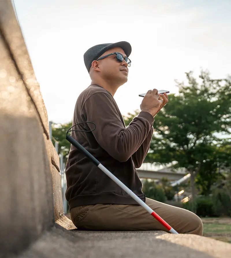 Young asian blind man using application on mobile phone to help accessibility for persons with visual impairment. California services for the blind.