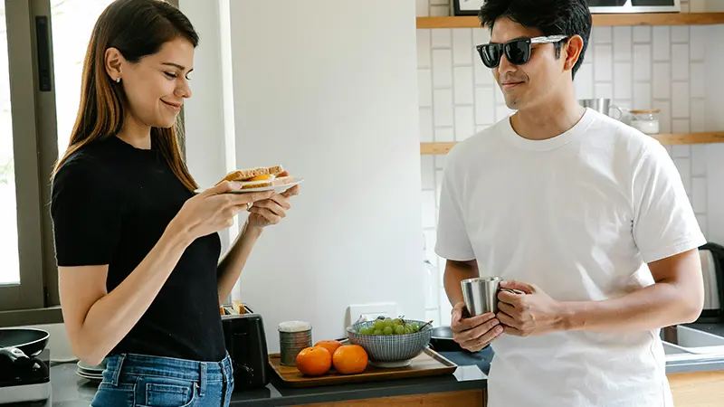 Services for people with vision loss showing a blind man standing in his kitchen drinking a cup of coffee.