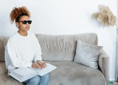 African American woman sitting on gray couch with vision impairment and mental health issues